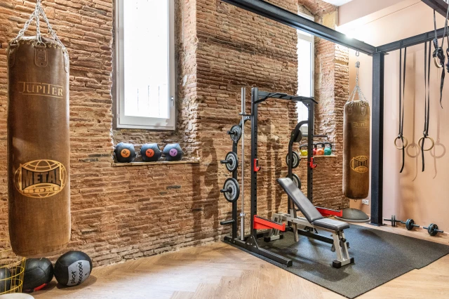 studio de sport moderne et bien équipé de l'Hôtel Ovyo Toulouse, avec des équipements de cardio et de musculation de pointe, des miroirs muraux pour le suivi de la posture, et une ambiance motivante 